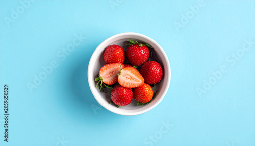 Strawberry in white bowl on blue background