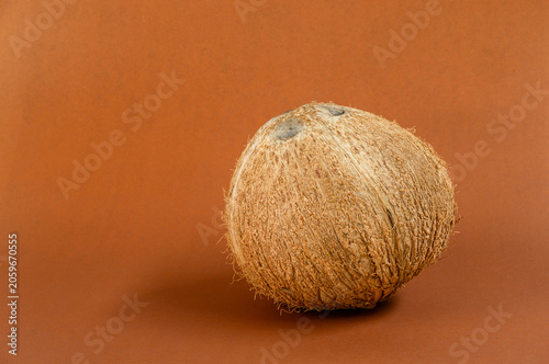 Coconut, Whole dried coconut on brown background with warm natural tone, Tropical fruit, highlighting texture, ideal for food, ingredients, and rustic minimal design