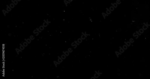 Super slow motion falling snow or dust particles isolated on a black background. Abstract atmospheric SFX overlay with floating debris, cinematic texture and dark visual effect.