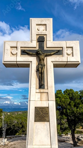 Large stone cross with Jesus statue, set against a blue sky