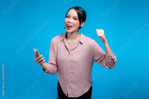 Happy Indonesian woman checking smartphone and celebrating good news