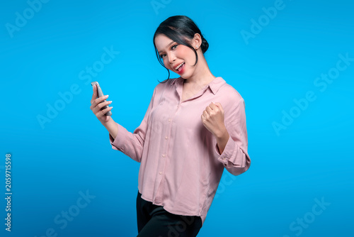 Excited Indonesian woman celebrating success with smartphone