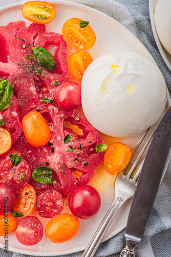 Burrata cheese with organic  yellow and red tomatoes, basilic and herbs. Summer Italian lunch