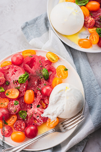 Burrata cheese with organic  yellow and red tomatoes, basilic and herbs. Summer Italian lunch