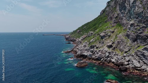 Rugged green coastline of Okinoshima Island viewed by drone