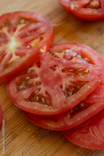 Close-up of fresh, juicy red tomato slices neatly arranged on a rustic wooden cutting board