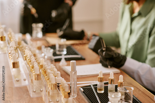 Fotografie Close up of middle aged woman filling cosmetic serum bottles and recording notes during product testing