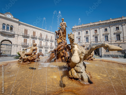 The Fountain of Diana and grand vintage buildings in Piazza Archimede, Ortigia, Syracuse, Sicily, Italy. Sunny day view of the historic town square architectural landmark.