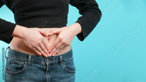 Happy female showing love with hand heart shape gesture on stomach belly promoting positive holistic gut health wellness care