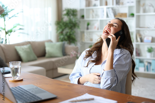 Фотография Happy teleworker laughing loud talking on phone