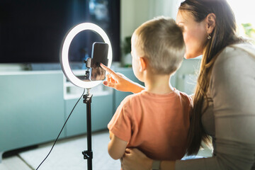 Mother live streaming with son on smart phone with ring light at home