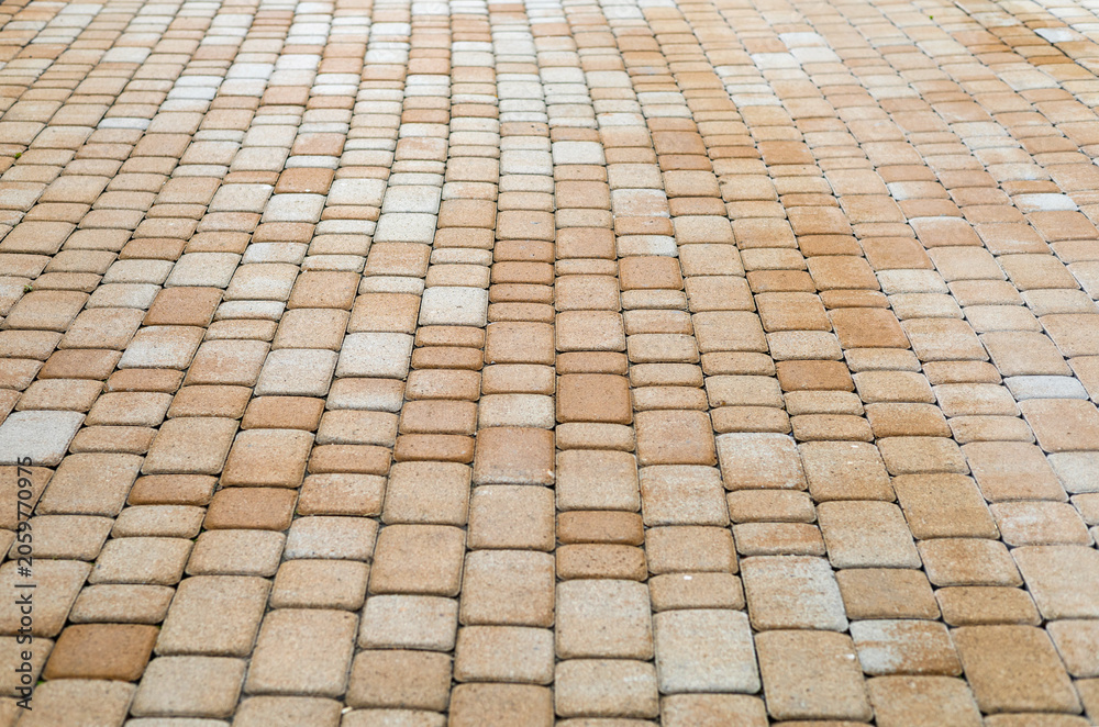 Fototapeta premium Close-up texture of beige concrete paving stones. Interlocking paving blocks laid in a decorative pattern for sidewalks, patios, driveways and landscape design.
