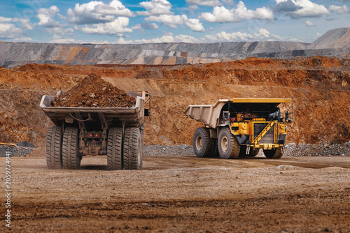 Bild auf Leinwand Two heavy dump trucks in open pit mine with gold ore carrying ore for industrial