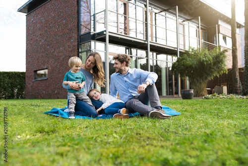 Happy family on blanket in garden in front of their home