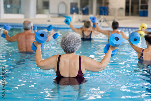 Senior aqua fitness class following instructor in indoor swimming pool