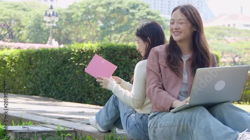 Two Asian University Students Studying Back to Back in a Sunny Park