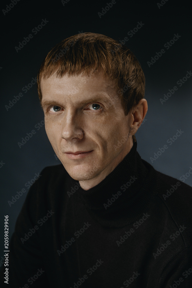 Fototapeta premium Portrait of a person with short hair and a black sweater looking at the camera indoors
