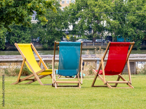 Fotografía Three vibrant colorful deck chairs inviting relaxation on green grass beside the
