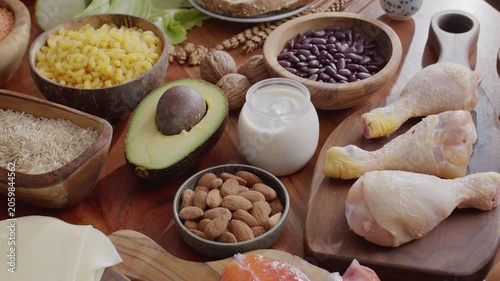 Slow camera movement along healthy food ingredients laid out on a wooden background: meat, fish, grains and vegetables.