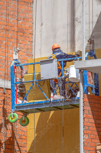 A man insulates the facade of a building on a summer day