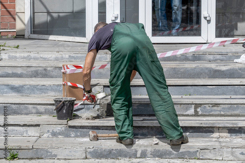 A man repairs the porch steps on a summer day