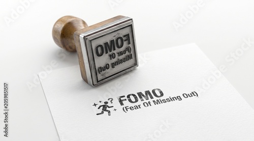 FOMO Fear Of Missing Out rubber stamp on white paper, psychological social anxiety concept, wooden handle stamper with black ink text