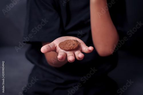 Photos Close up high angle shot of an Asian boy holding a single chocolate chip cookie