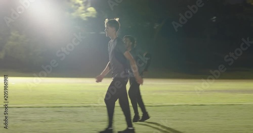 Teammates bouncing in floodlit huddle after fielder running to chase batsman swinging bat