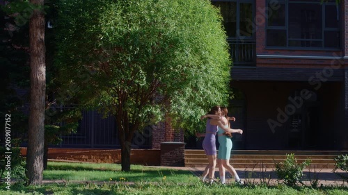 Two happy twin sisters finishing their run, giving a high five and hugging each other in a park
