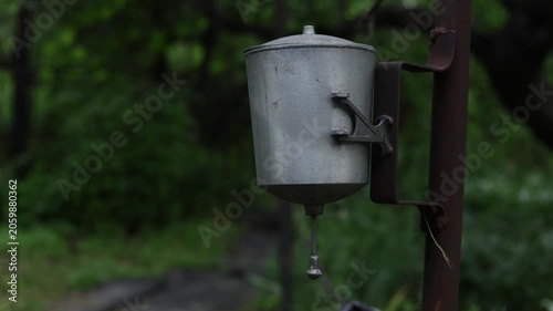 Vintage metal water dispenser with a single drop falling in a lush green forest setting