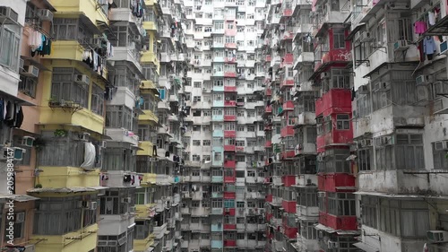 Upwards tilting drone shot of people drying laundry in dense residential apartment tower in Quarry Bay district of Hong Kong
