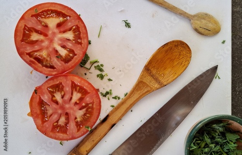 Tomates, persil et ustensiles de cuisine sur une planche de découpe. Préparation d'un plat méditerranéen frais.