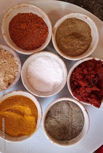Ensemble de petits bols contenant des épices : sel, paprika, cumin, poivre noir, gingembre, curcuma pour la réalisation de spécialités culinaires marocaines, méditerranéennes