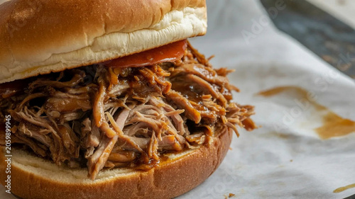 Pulled pork sandwich close up, shredded barbecue meat on bun with sauce, rustic comfort food for menu and ads