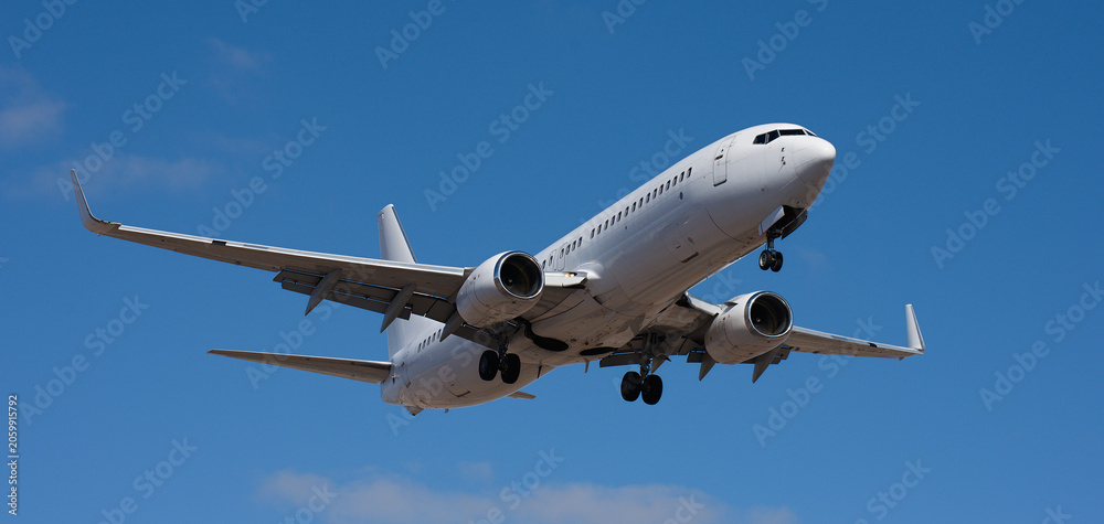 Fototapeta premium The plane lands. Airplane, passengers flying in the blue sky, preparing to land at the airport