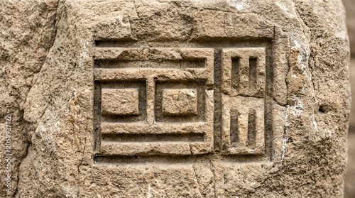 Ancient stone carving with geometric symbols, close-up detail of weathered rock texture.