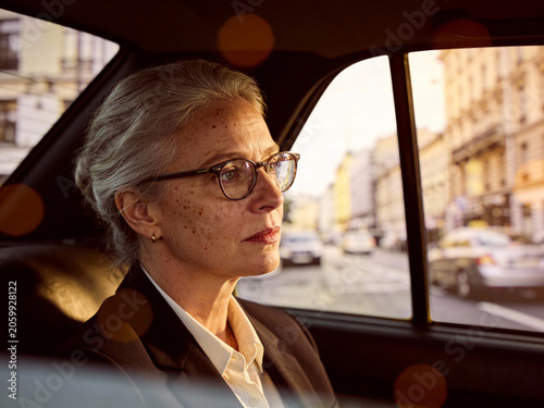 Porträt einer eleganten Frau mit Brille und grauen Haaren im Auto
