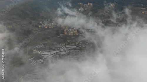 Drone shot of classic stone houses with straw rooftops in small village, set in rice terraces of Yuanyang in Southern China
