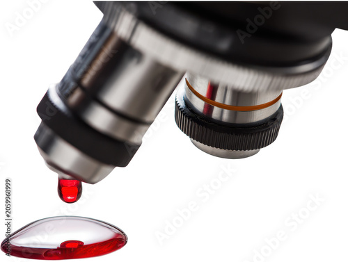 Close-up of a microscope with a droplet of red liquid on a glass slide for scientific research