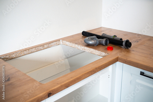 Foto Sink plumbing parts on a wooden countertop with cutout for installation