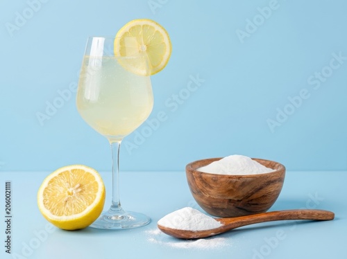 A refreshing lemonade beverage with fresh lemon slices and a bowl of powder, perfect for summer refreshment
