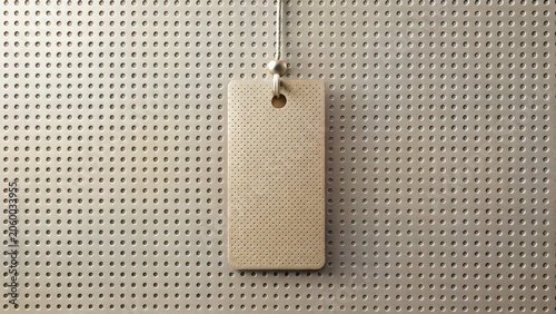 A hanging perforated tag mockup against a textured background of small circular holes