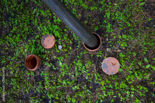 Septic suction hose pumping domestic wastewater in backyard drainage system. Concept: septic service