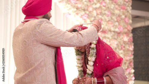 Sikh Groom Putting White Rose Varmala On Bride During Traditional Wedding Ceremony