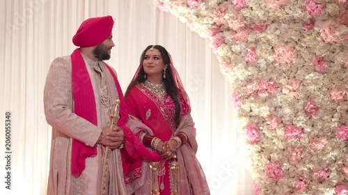 Traditional Sikh Bride and Groom Standing on Reception Stage Looking at Eachother