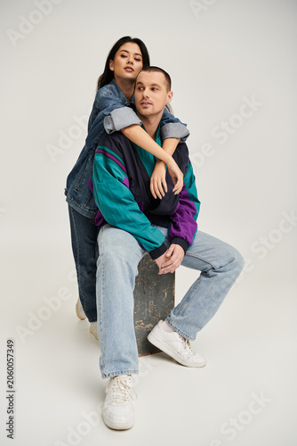 Schilderij op canvas A beautiful young couple poses in fashionable outfits, radiating love and connection in a studio
