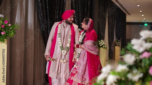 Romantic Punjabi Newlyweds Holding Hands After Varmala Ceremony In Elegant Hallway