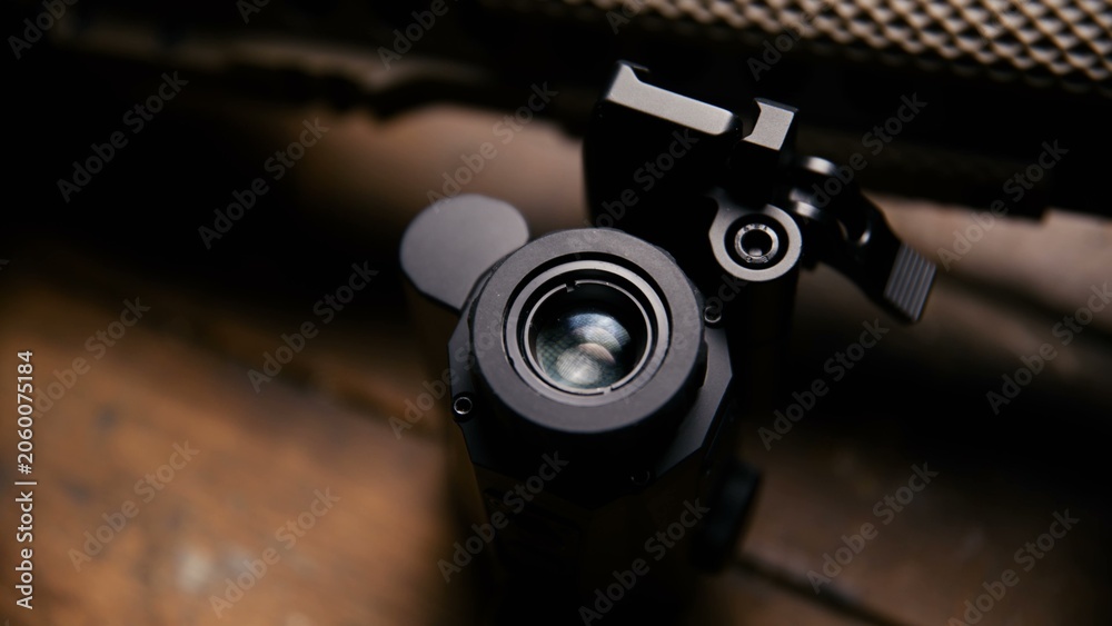 Obraz premium A close view of a black tactical scope attached to a textured metallic rail system on a rifle frame showing mounting hardware and lens housing components on a professional grade weapon