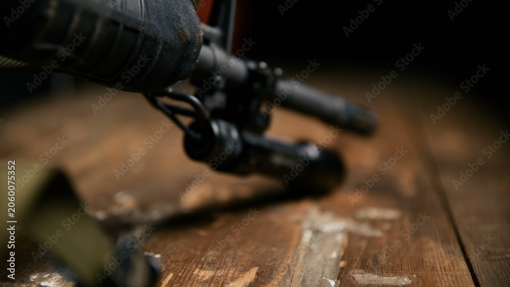 Obraz premium A low angle view of a black tactical flashlight attached to a rifle barrel housing resting on a rustic wooden table surface highlighting professional firearm illumination accessories