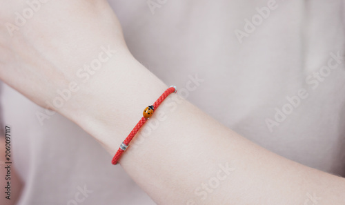 ladybug on the red bracelet on woman's hand